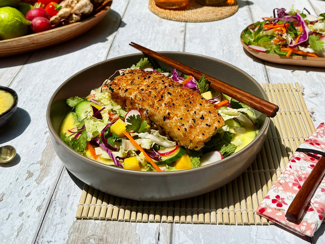 Bowl of salad with grilled fish on a wooden table