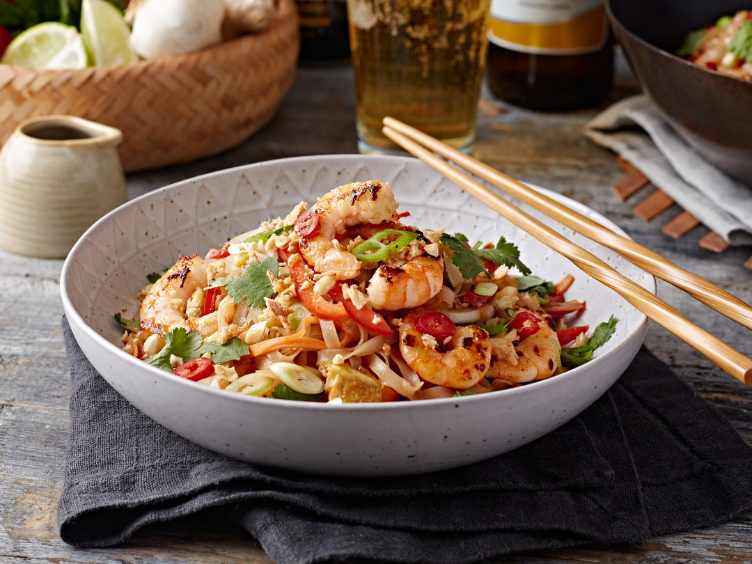 Bowl of shrimp stir-fry with chopsticks on a wooden table