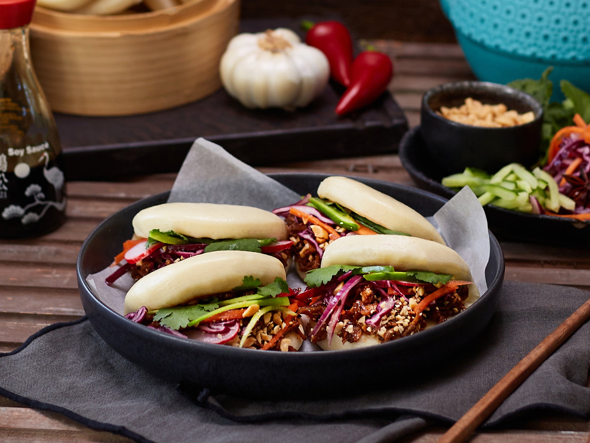 Bao buns with vegetables on a dark plate on a wooden table.