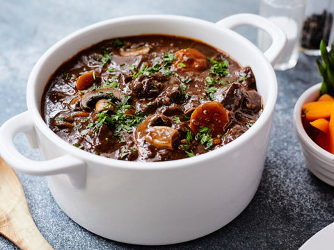 White bowl filled with beef stew on a gray surface