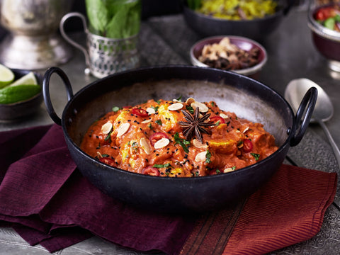 Stir-fried dish with vegetables and spices in a dark bowl on a textured surface.
