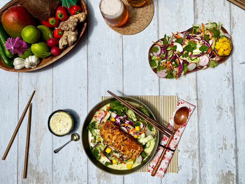 Salad with salmon and vegetables on a wooden table with fruits and drinks.