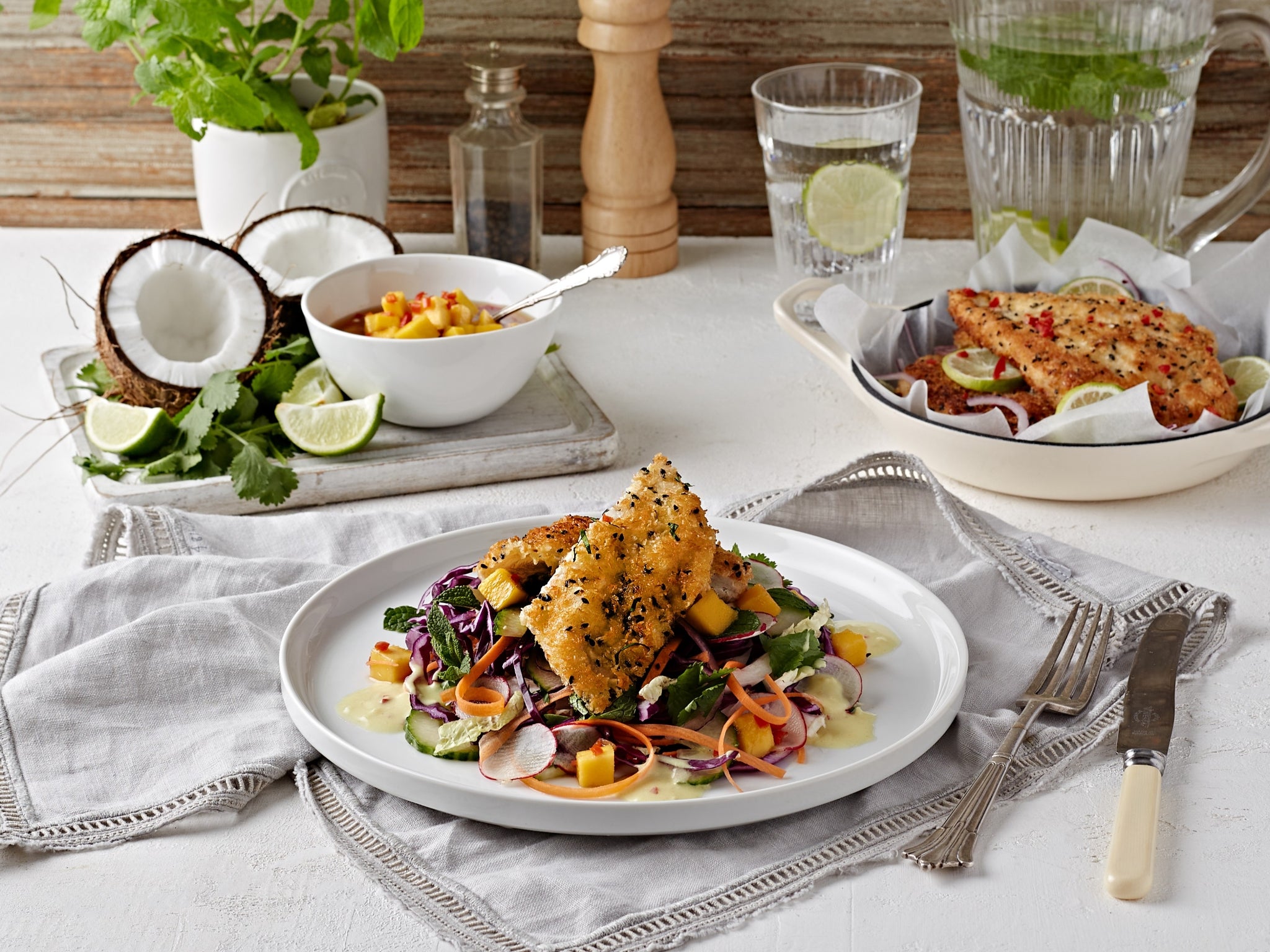 Dinner table setting with a plate of food, salad, and drinks.