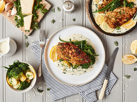 Plated dish of chicken with vegetables on a wooden table with side dishes.