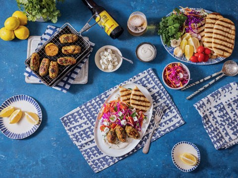 Assorted food items including grilled items, vegetables, and sauces on a blue tablecloth.