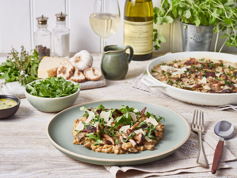 Table setting with a dish of risotto, salad, and wine.