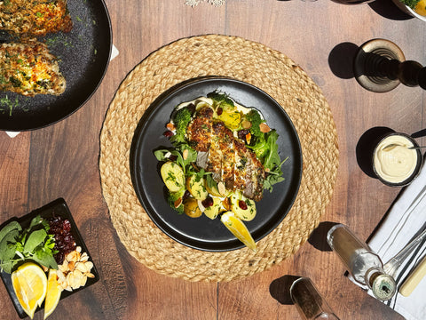 Plated dish of food on a wooden table with cutlery and glasses.
