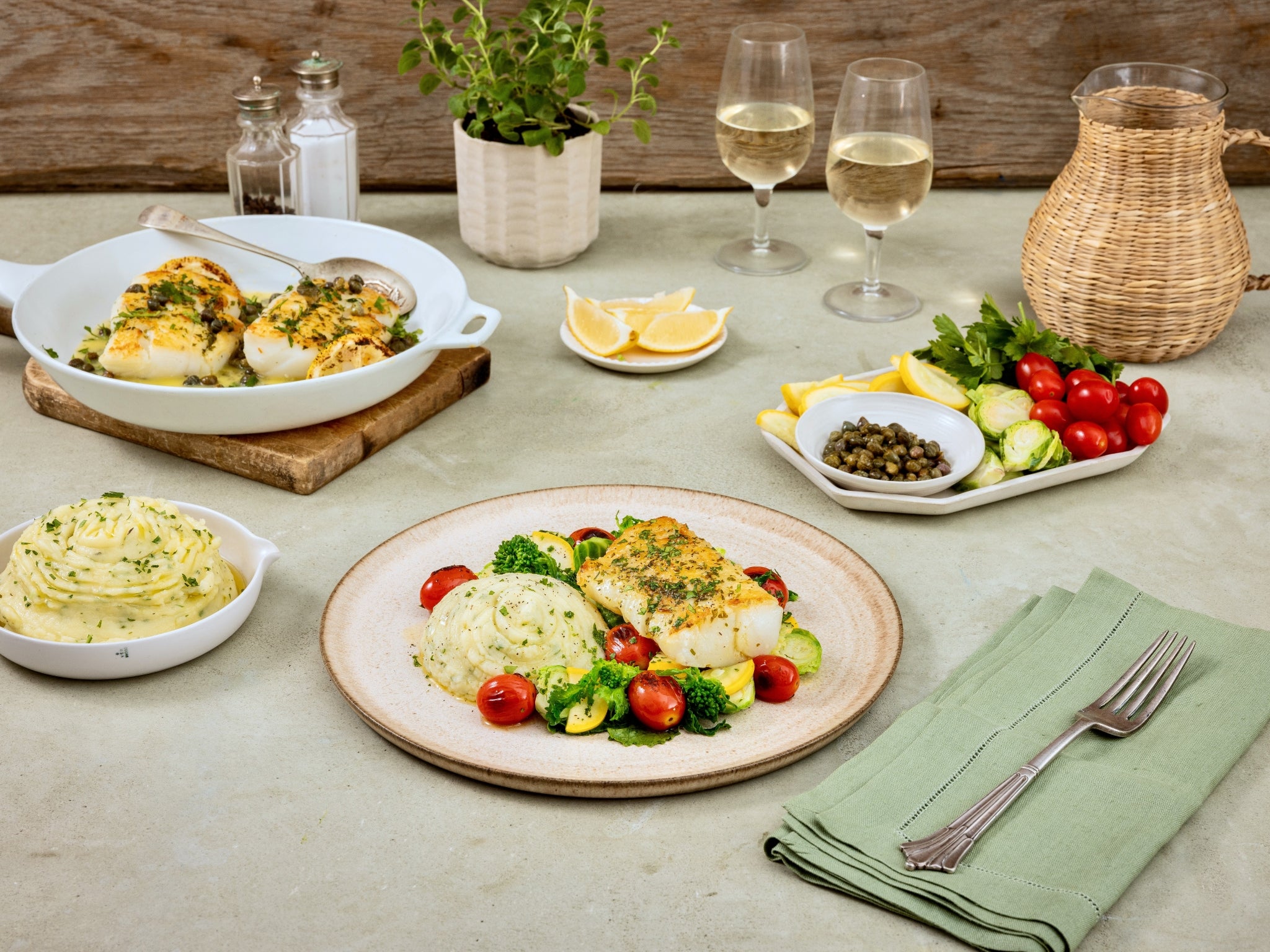 Dining table set with a meal including fish, vegetables, and side dishes.