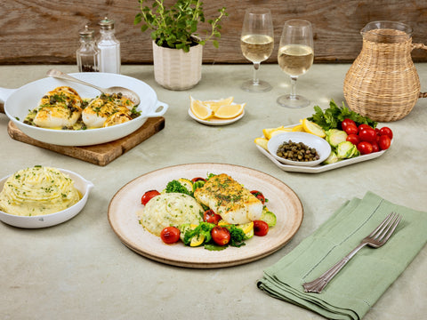 Dining table set with a meal including fish, vegetables, and side dishes.