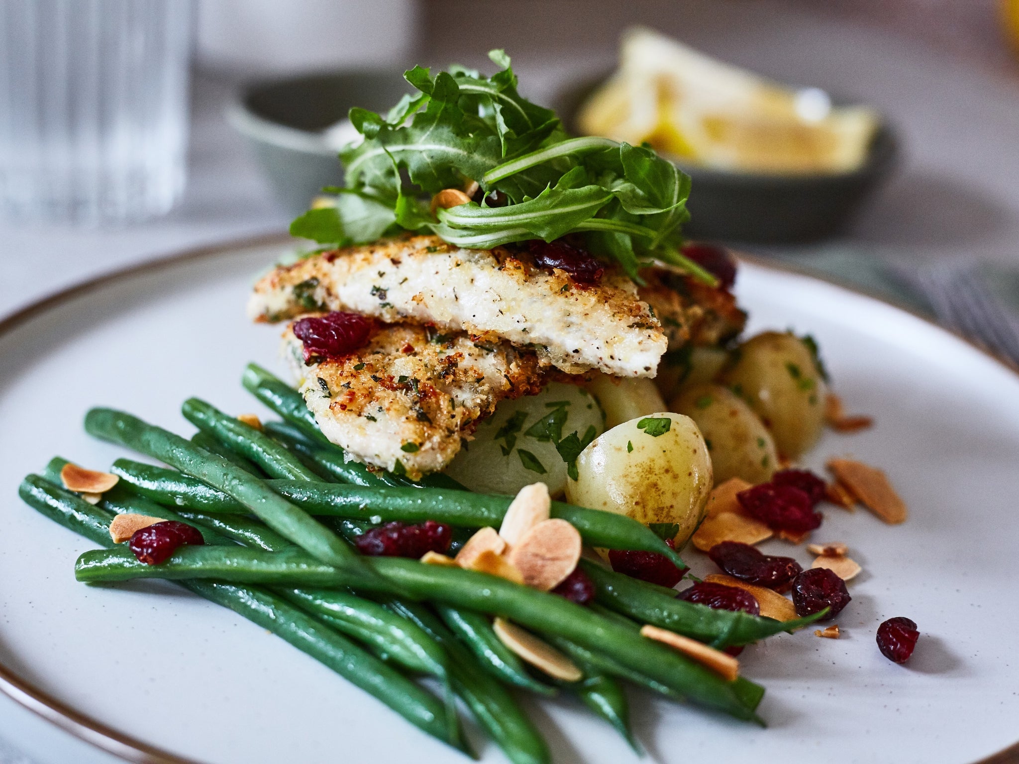 Plated dish with fish, green beans, and potatoes on a white plate.