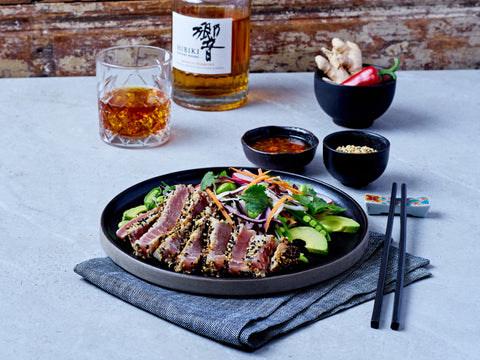 Plated dish of tuna salad with a glass of beer and bottles in the background