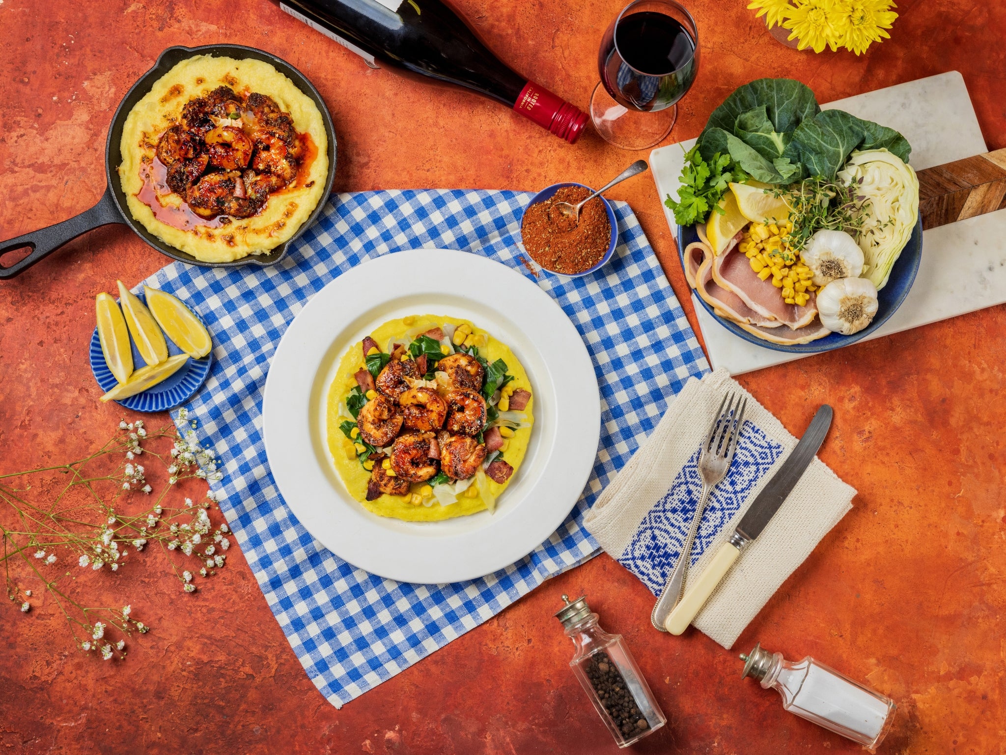 Dinner table setting with a plate of food, wine, and cutlery on a checkered cloth.