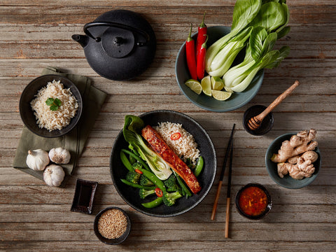 Dinner setup with rice, vegetables, and a teapot on a wooden table.