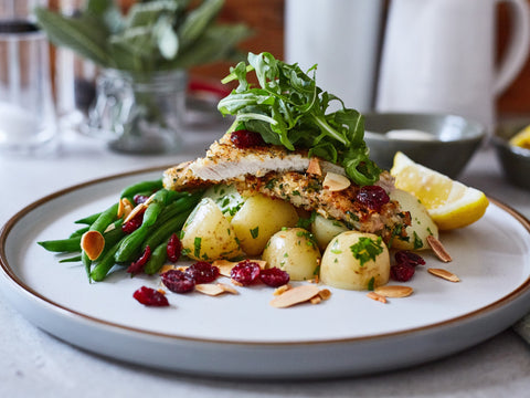 Plated dish with chicken, potatoes, green beans, and salad on a white plate.