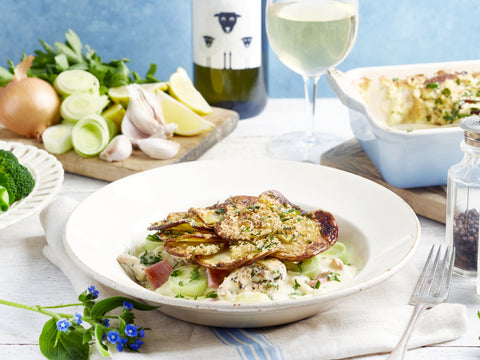 Dish of food on a table with a bottle of wine and a glass.