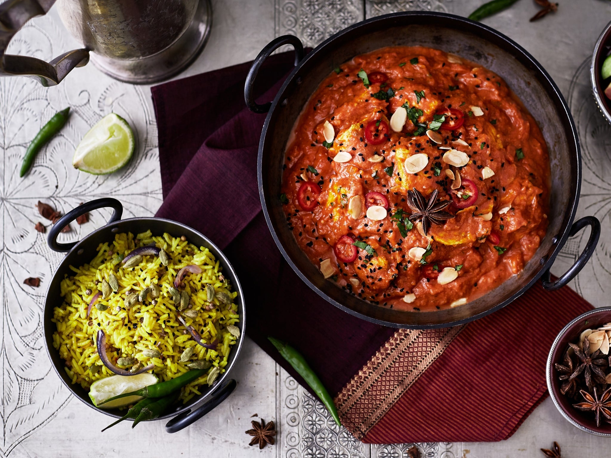 Two bowls of different types of food on a patterned surface with garnishes.