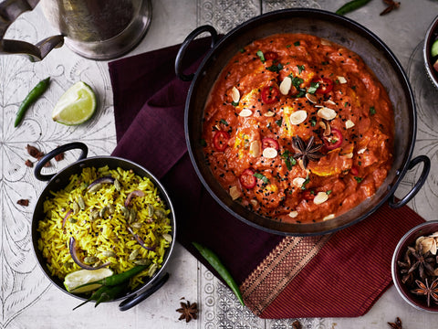 Two bowls of different types of food on a patterned surface with garnishes.