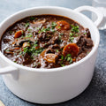 White bowl filled with beef stew on a gray surface